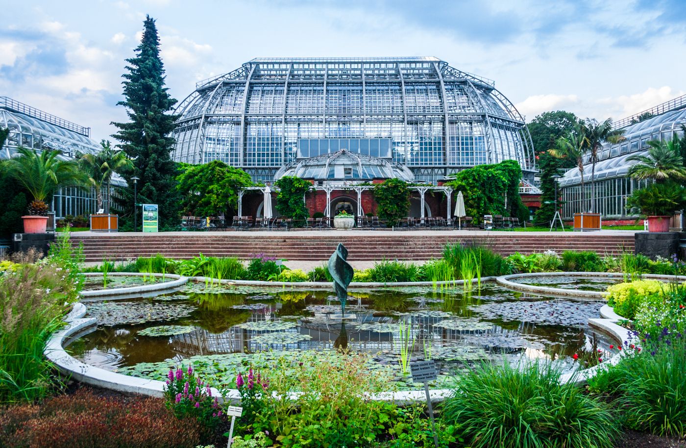 An open bamboo pavilion structure among tropical plantings at a botanical garden