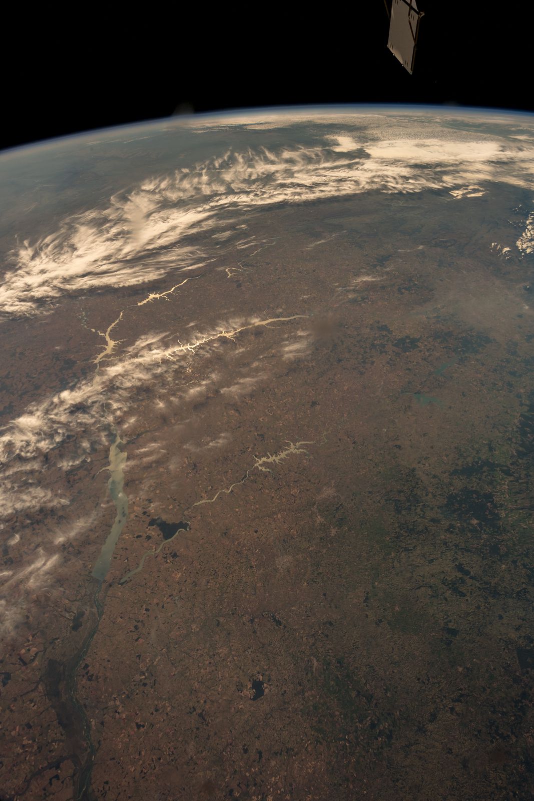 Aerial view of dense green Amazon rainforest canopy stretching to the horizon under a partly cloudy sky in Brazil