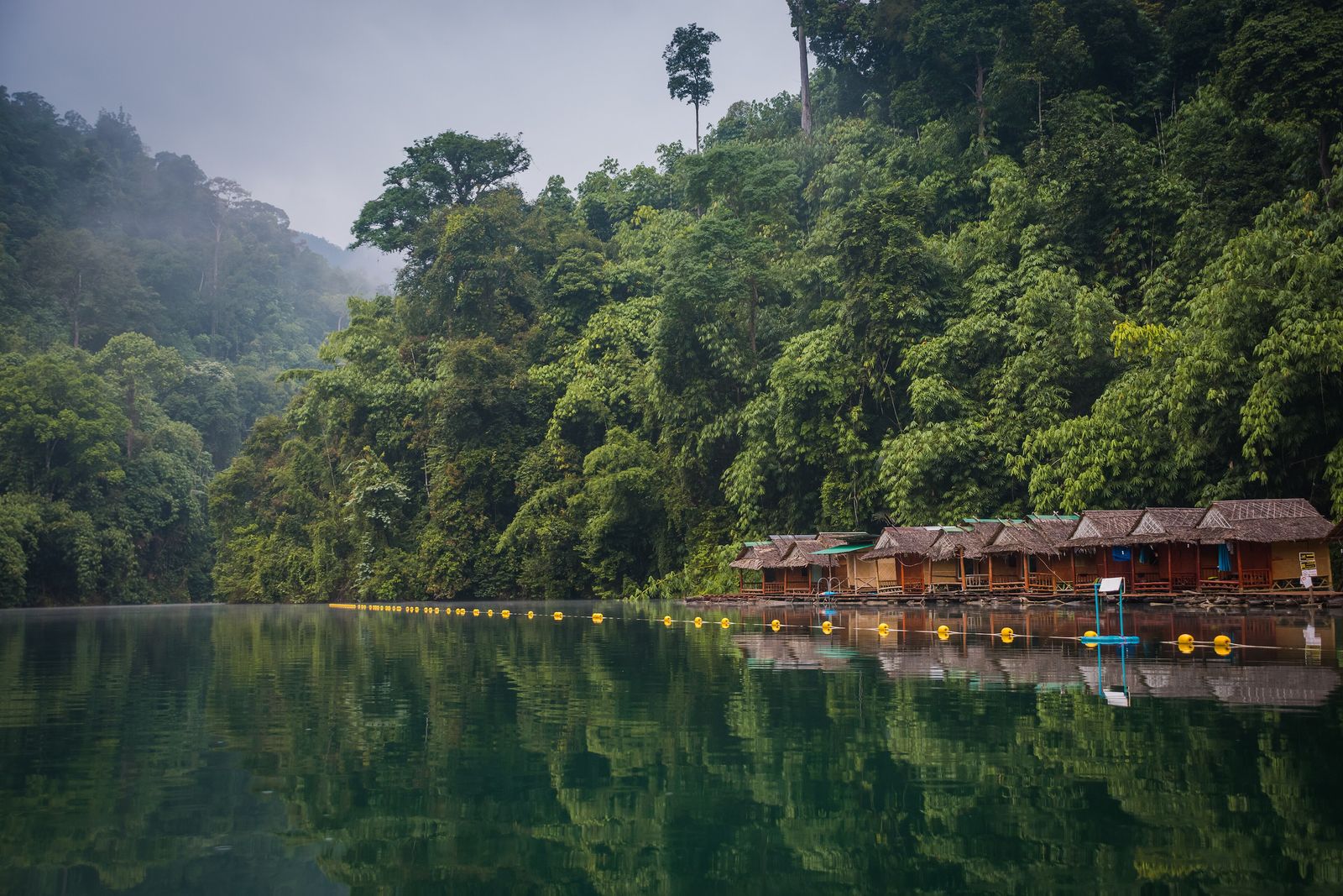 A wooden floating bungalow raft house on Cheow Lan Lake in Khao Sok National Park, Thailand, surrounded by limestone karst cliffs